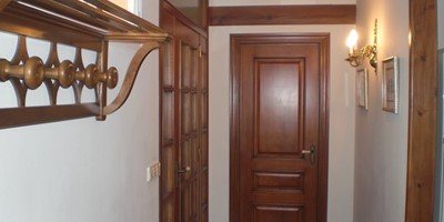 Vestíbulo de la casona con puertas y perchero de madera